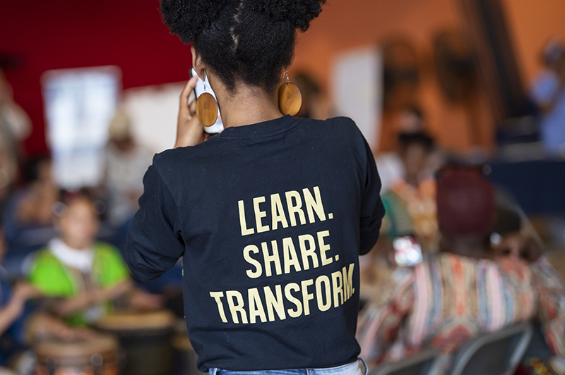 person wearing a shirt that reads Learn. Share. Transform.